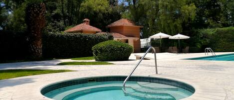 A circular hot tub with a metal ladder, surrounded by a tiled deck.
