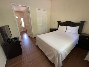 Un dormitorio con cama, mesita de noche, cómoda y televisor.