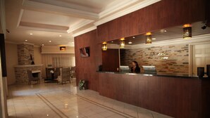 En hotellobby med en receptionsdisk i trä, en stor spegel och en vägg av sten.