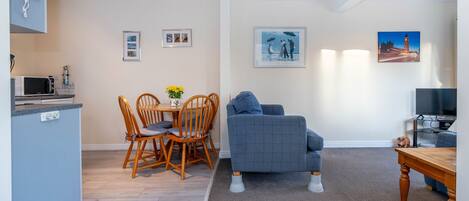 Un espacio habitable compacto con kitchenette, comedor y zona de estar.