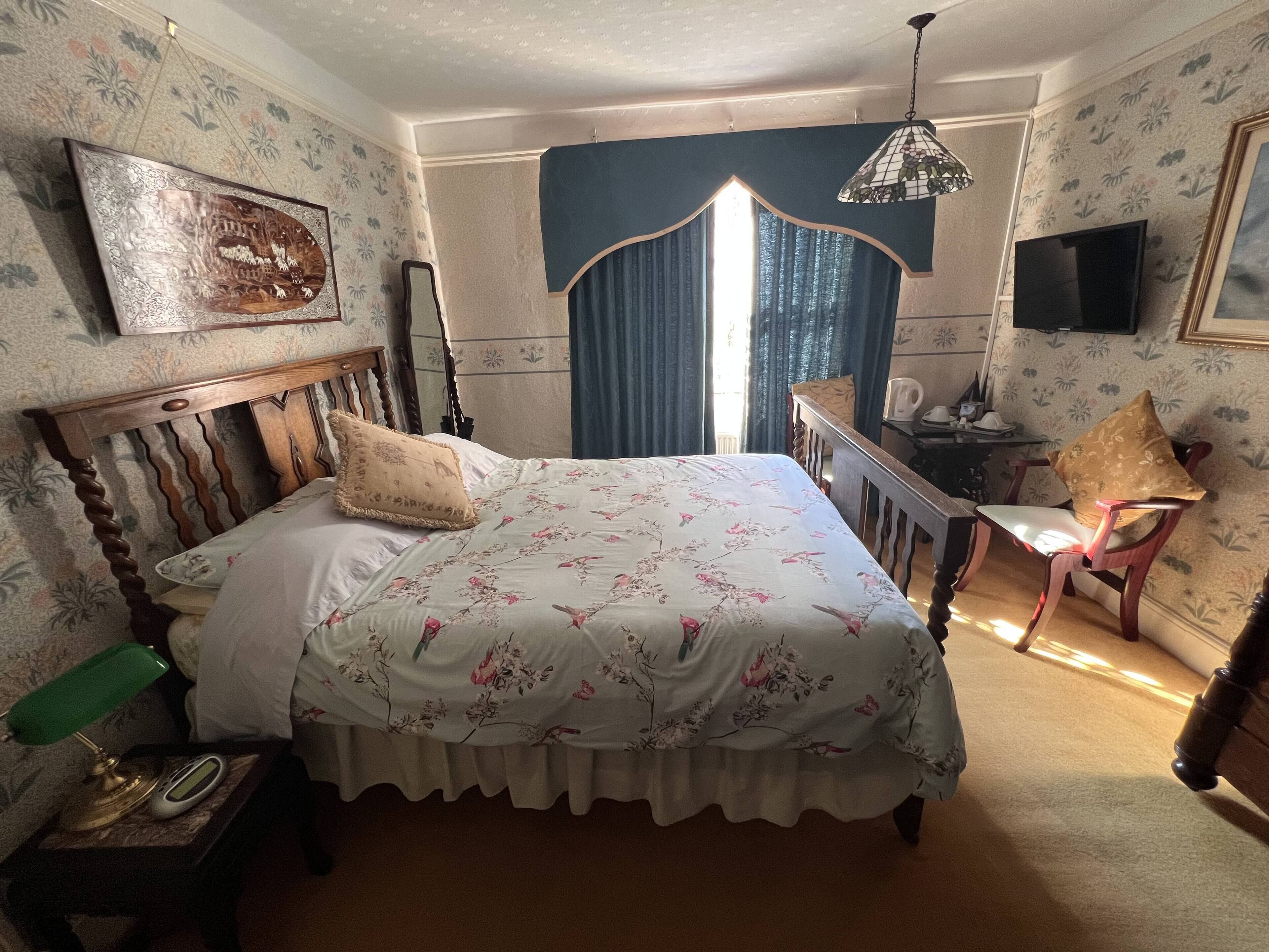 Un dormitorio con cama, escritorio, silla, televisión y espejo.