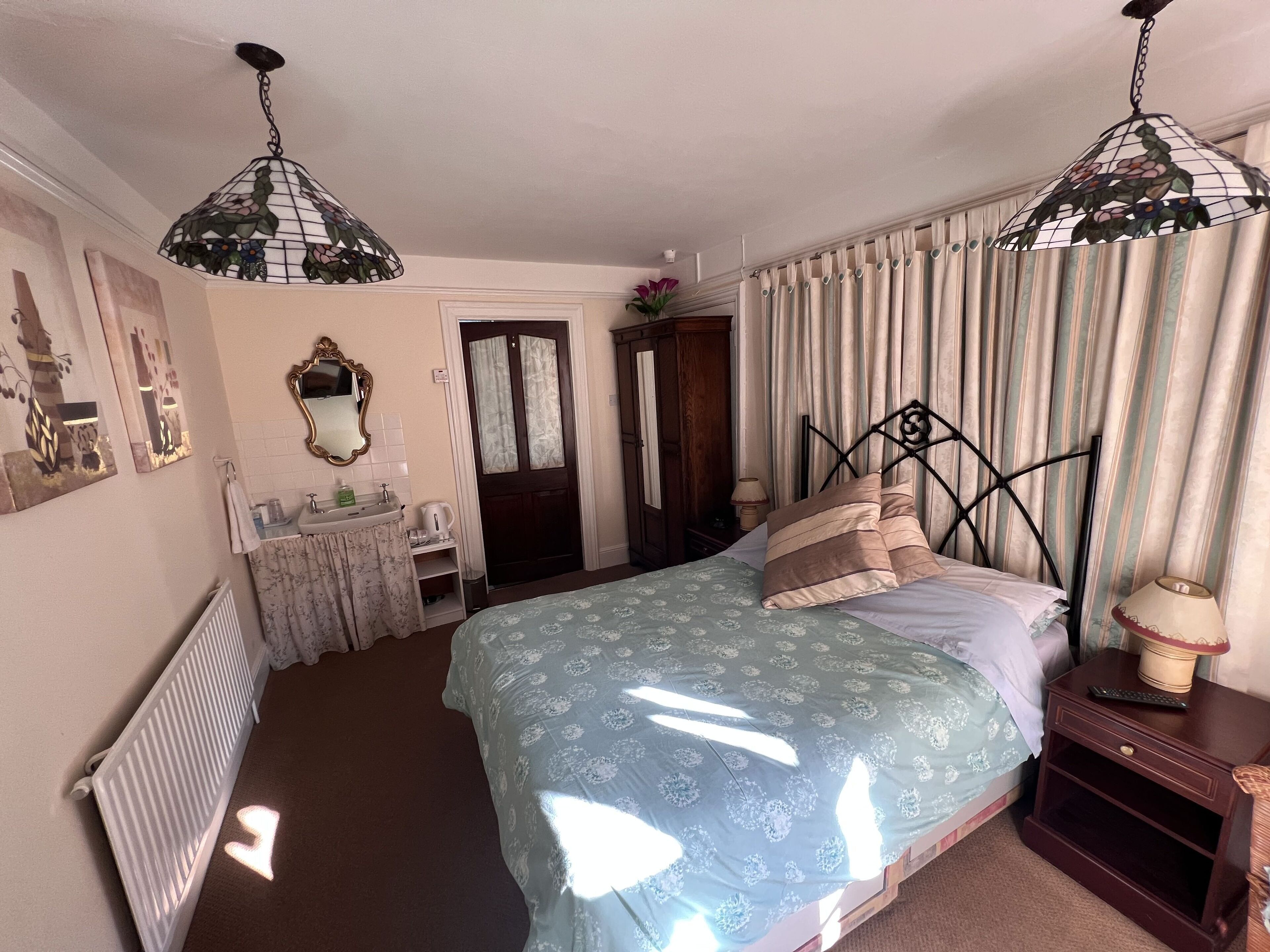 A bedroom with a bed, bedside table, and a hanging light fixture.