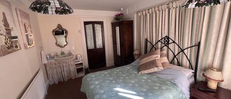 A bedroom with a bed, bedside table, and a hanging light fixture.