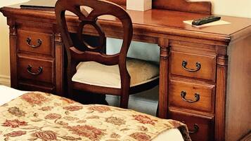 A wooden dresser with a mirror, a chair, and a bed with a floral bedspread.