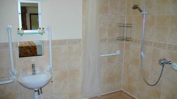Un baño con lavamanos, espejo, ducha y toallero.