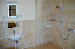 Un baño con lavamanos, espejo, ducha y toallero.