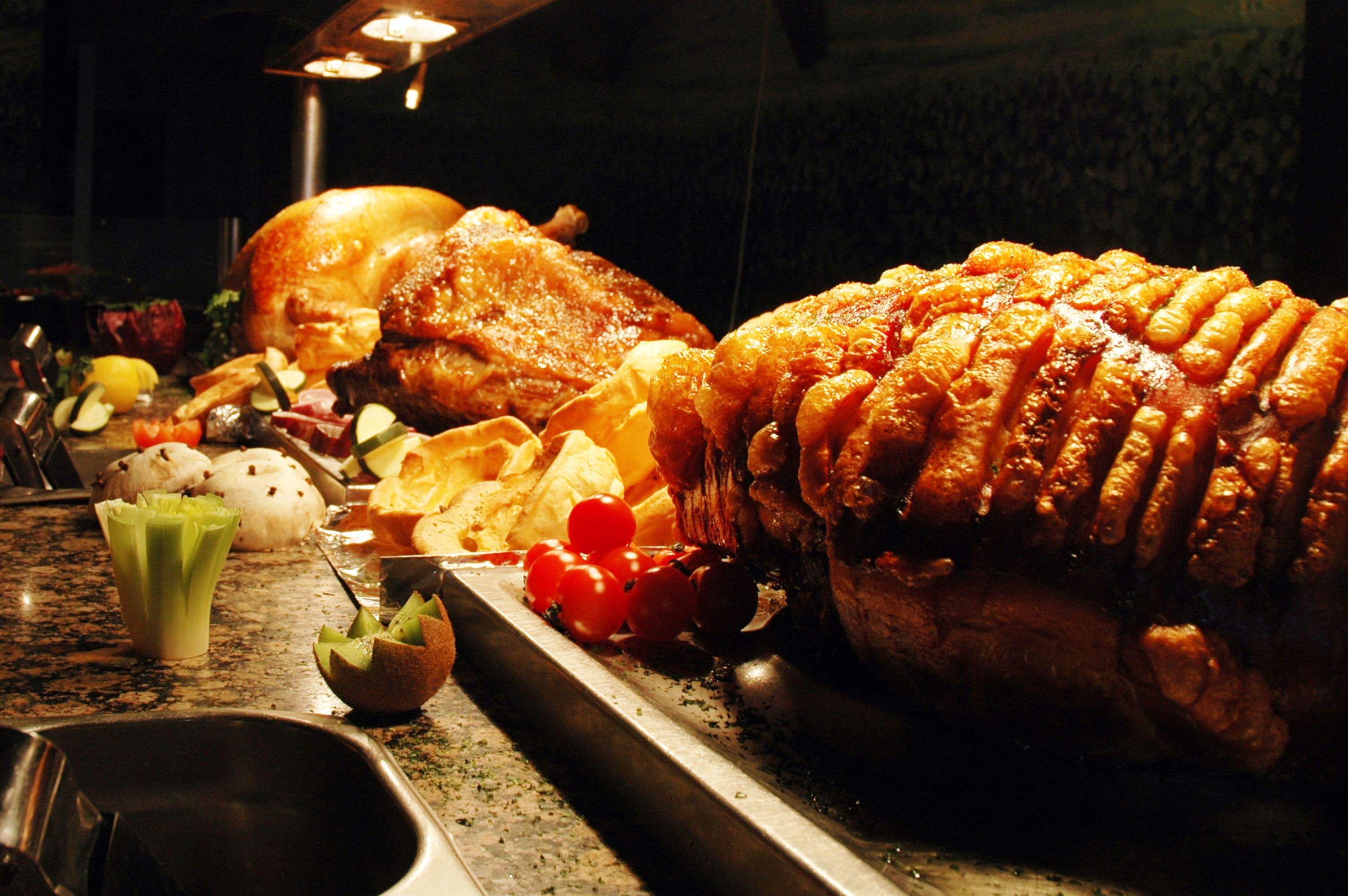 A roasted turkey surrounded by various vegetables and fruits on a serving tray.