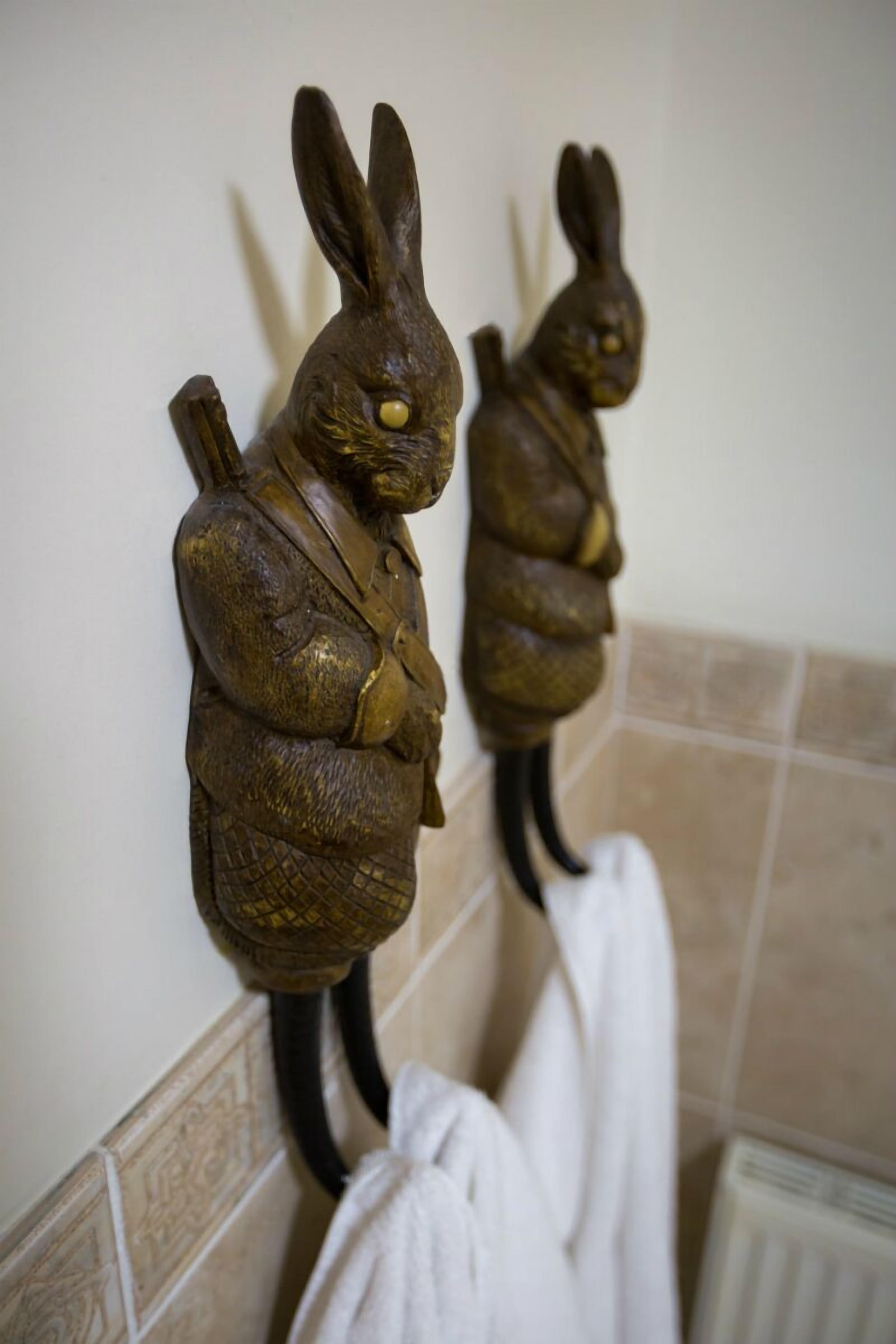 Two wall-mounted rabbit sculptures in a bathroom with a towel hanging below.