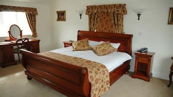 A bedroom with a wooden bed, a nightstand with a lamp, a dresser, and a mirror.