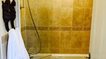 A bathroom with a bathtub, a shower, and a towel rack with towels.