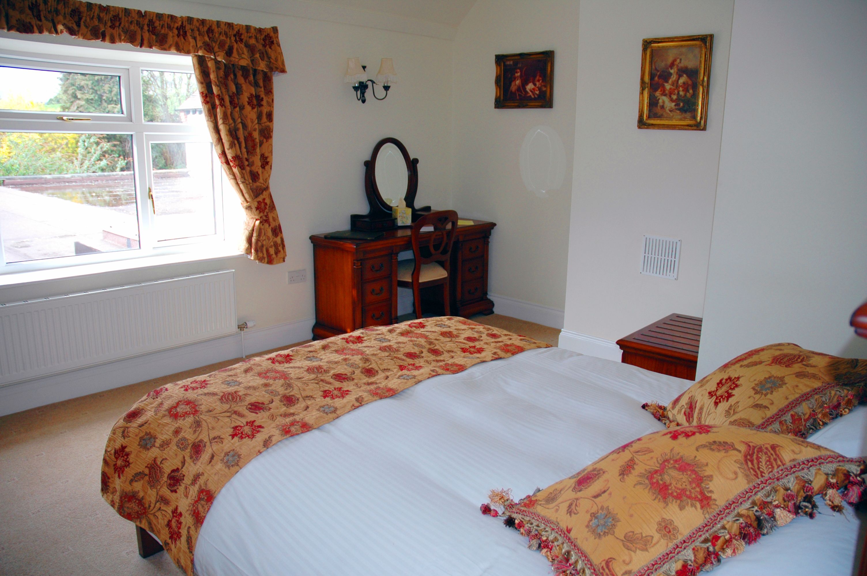A bedroom with two beds, a dresser, a mirror, and a window with curtains.