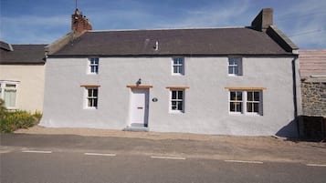 A two-story house with a white exterior, a grey roof, and a chimney.