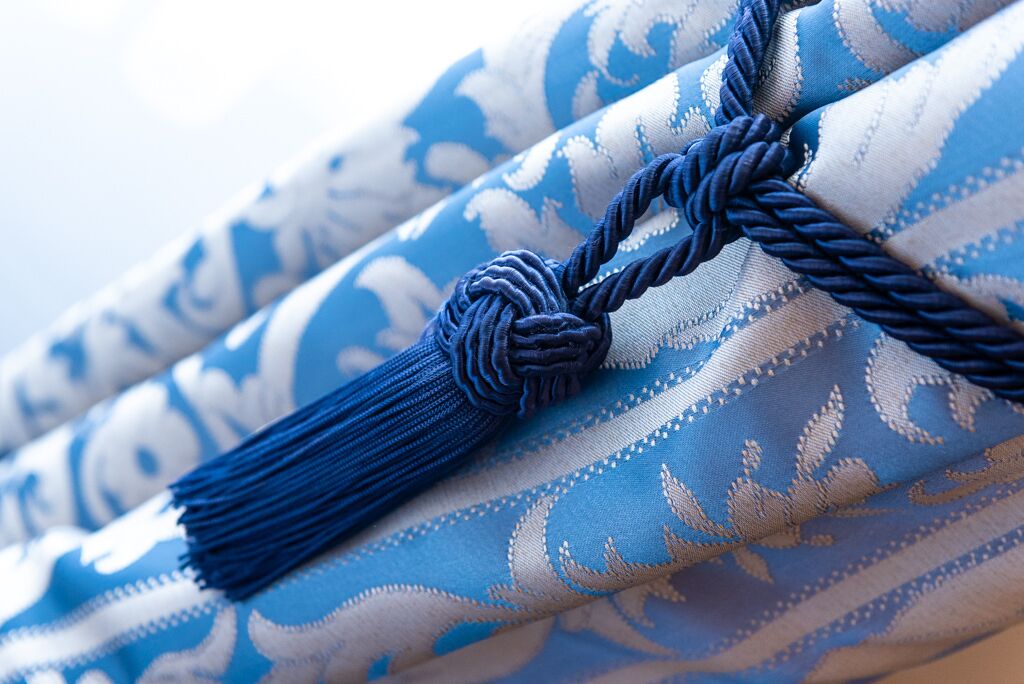 A close-up of a fabric with a blue and white pattern and a blue tassel.