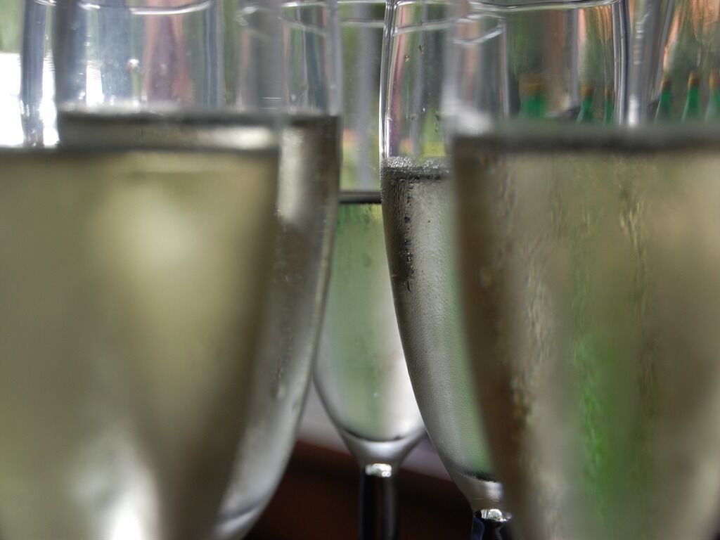 A close-up of several glasses filled with a clear liquid, likely water or a beverage, with condensation on the outside.