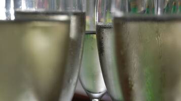 A close-up of several glasses filled with a clear liquid, likely water or a beverage, with condensation on the outside.