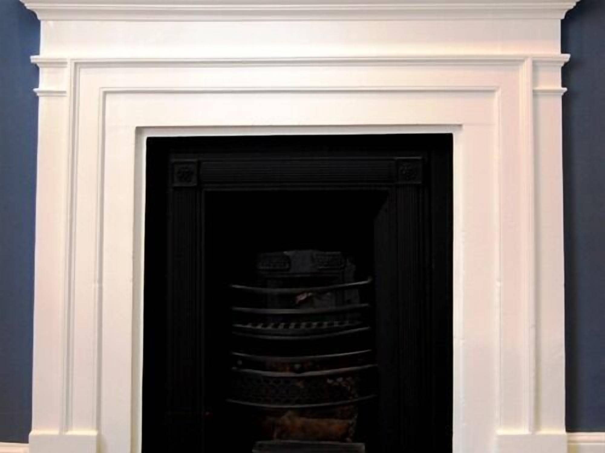Un interior oscuro con un vano de puerta enmarcado en blanco que da a una habitación de paredes negras.
