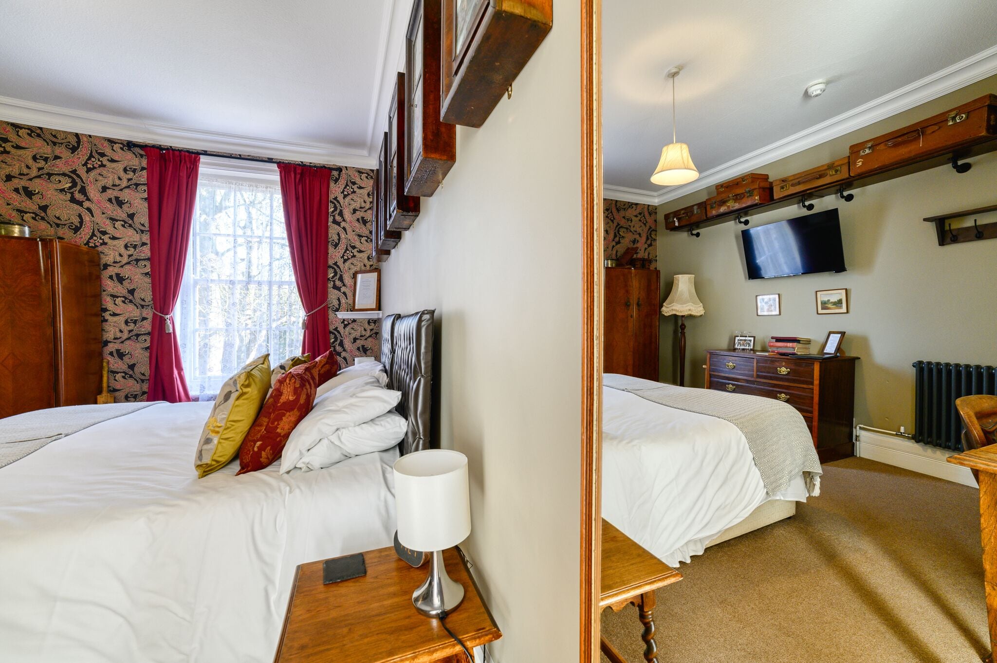 A hotel room with two beds, a television, a dresser, and a mirror.