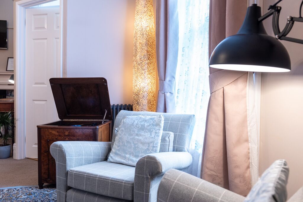 A cozy living room with a checkered sofa, a wooden side table, and a floor lamp.