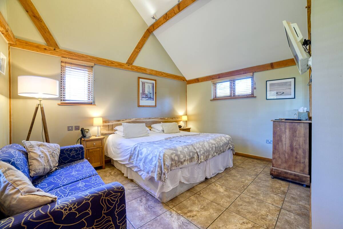 A bedroom with a bed, a sofa, a wooden cabinet, and two bedside lamps.