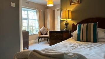 A hotel room with a bed, a nightstand, a lamp, a chair, and a window.