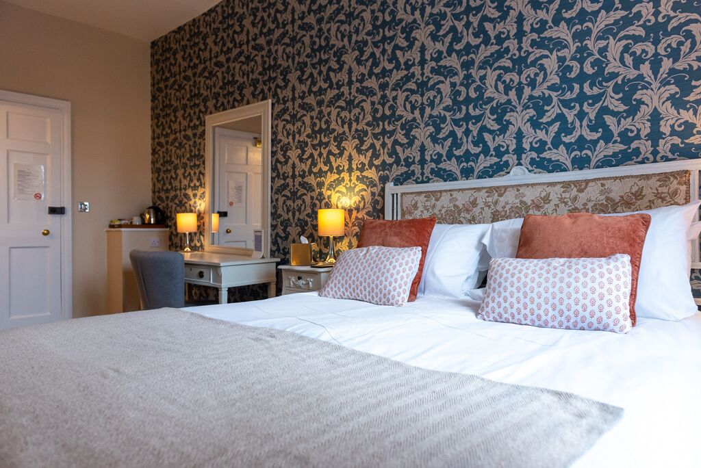A hotel room with a large bed, two bedside tables with lamps, a mirror, and a dresser.