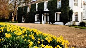 A large, two-story building with a white facade and green ivy covering the upper part. - The Grove Cromer (Cromer)