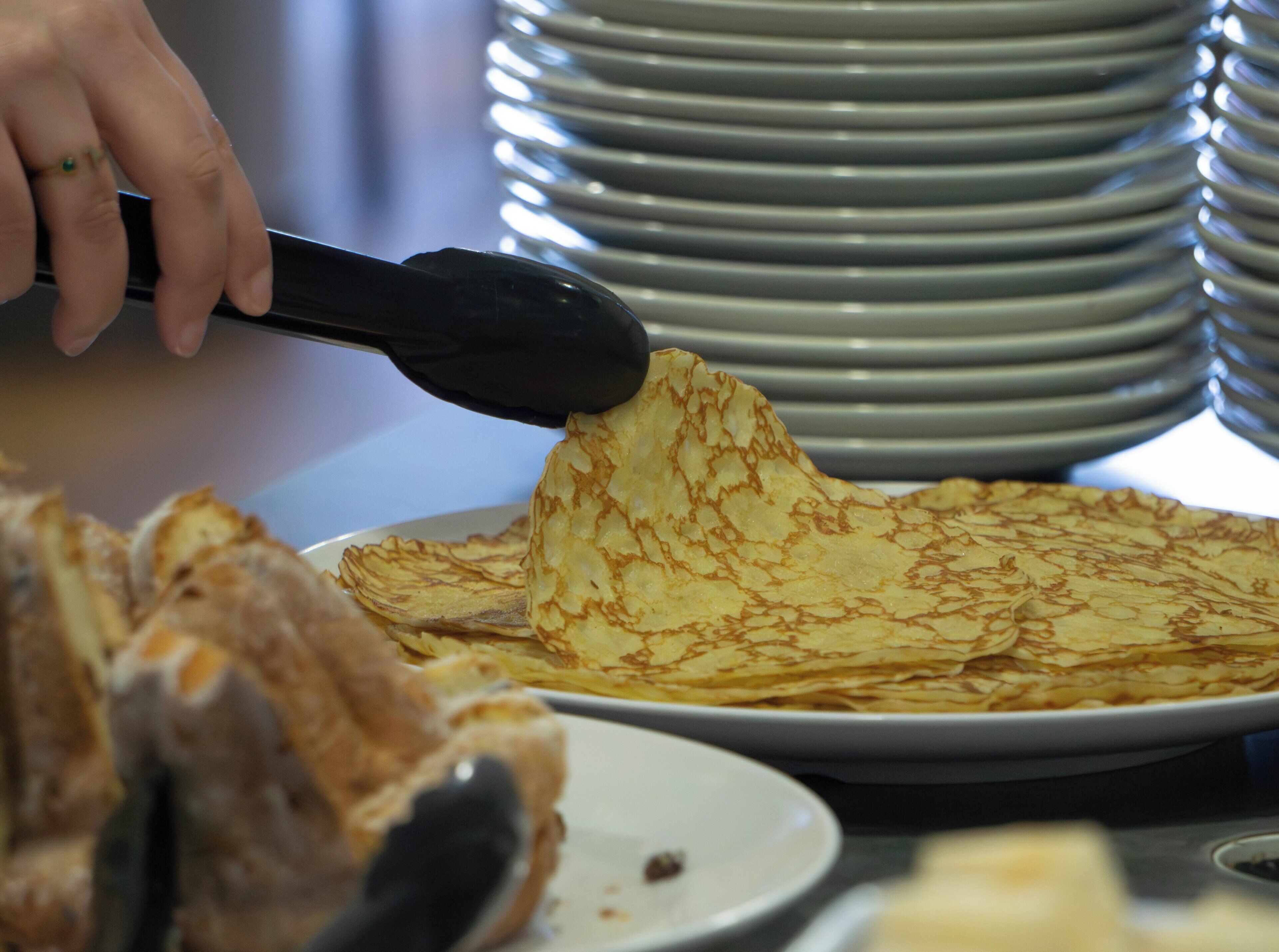 A stack of plates and a person using a spatula to serve food.