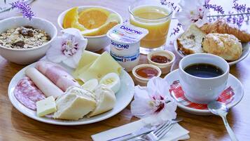 A breakfast table with various food items including eggs, cheese, bread, and a glass of orange juice.