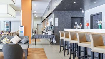 A modern hotel lobby with a bar area, seating, and a reception desk.