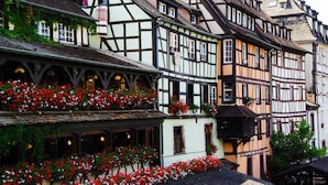 A traditional half-timbered building with multiple stories, balconies with red flowers, and a steeply pitched roof. - Holiday Inn Express Strasbourg - Centre by IHG (Strasbourg)