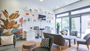 Una sala de estar moderna con un televisor de pantalla plana, un escritorio con una computadora y un comedor con sillas y una mesa.