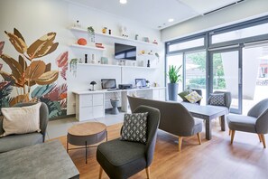 Un soggiorno moderno con una TV a schermo piatto, una scrivania con un computer e un'area pranzo con sedie e un tavolo.