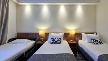 Hotellihuone, jossa on kaksi erillistä sänkyä, puinen pääty, yöpöytävalaisimet, puhelin ja pieni pöytä.