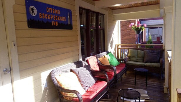 A cozy outdoor seating area with wicker furniture and a sign for the Ottawa Backpackers Inn. - Ottawa Backpackers Inn (Ottawa)
