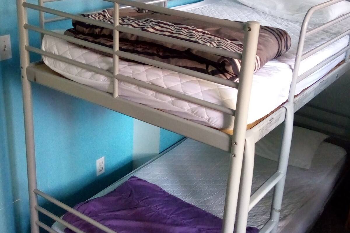 A bunk bed with two levels, each with a mattress and a blanket.