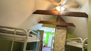A dormitory room with bunk beds, a ceiling fan, and a green door in the background. - Ottawa Backpackers Inn (Ottawa)