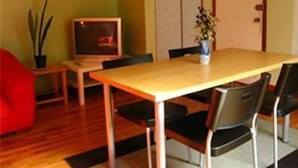 A dining area with a wooden table, two chairs, a small potted plant, and a television on a stand. - Ottawa Backpackers Inn (Ottawa)