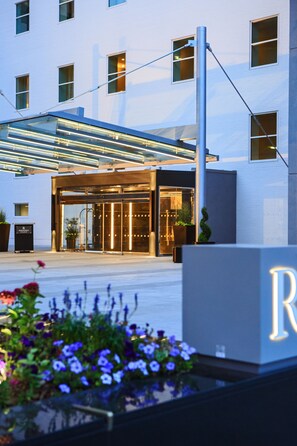 A modern hotel entrance with a glass facade, a metal canopy, and a sign with the letter 'R'. - Renaissance Denver Downtown City Center Hotel (Denver)