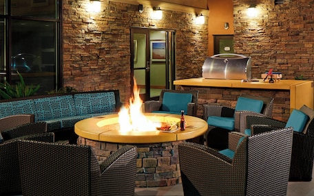 An outdoor seating area with wicker furniture, a stone wall, and a grill.