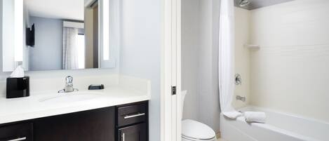Un baño moderno con un lavamanos blanco, muebles oscuros, un inodoro y una bañera.