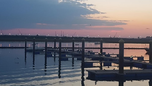 A waterfront pier with multiple docks extending into calm water, reflecting the sky. - Hostal Patio Andaluz (Punta Umbría)