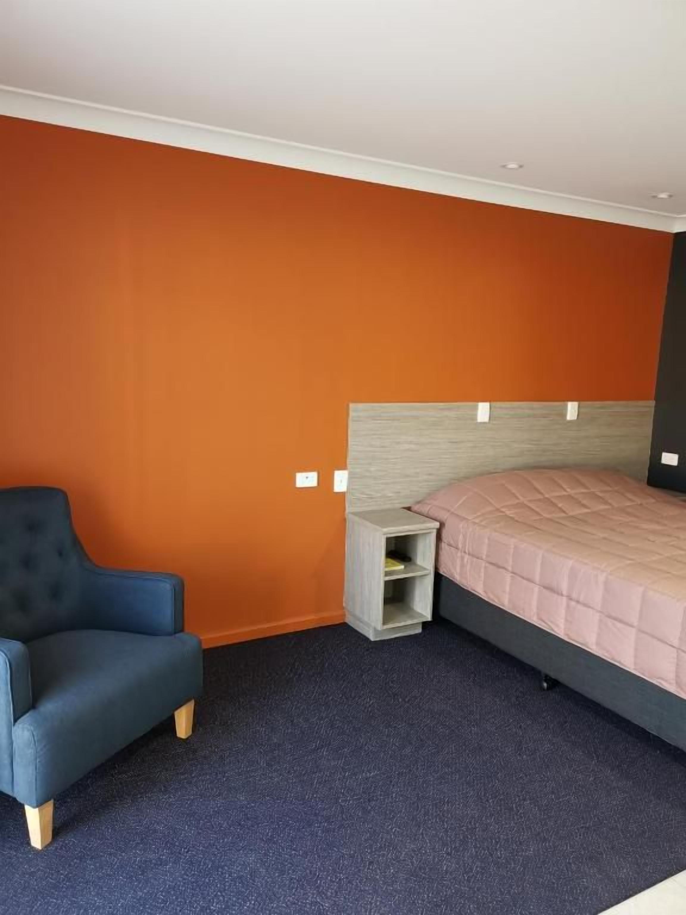 A bedroom with a bed, a chair, and a nightstand.