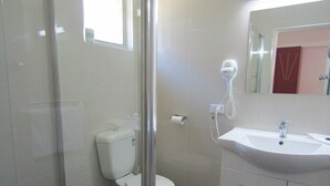 A bathroom with a toilet, a shower, and a sink. - Homestead Motel (Dubbo)