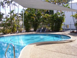 Una piscina al aire libre, sillones reclinables de piscina