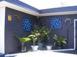A building exterior with a dark facade, decorative wall art, and potted plants.