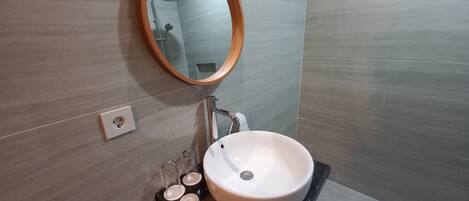 A bathroom with a round mirror, a white sink, and a black countertop.