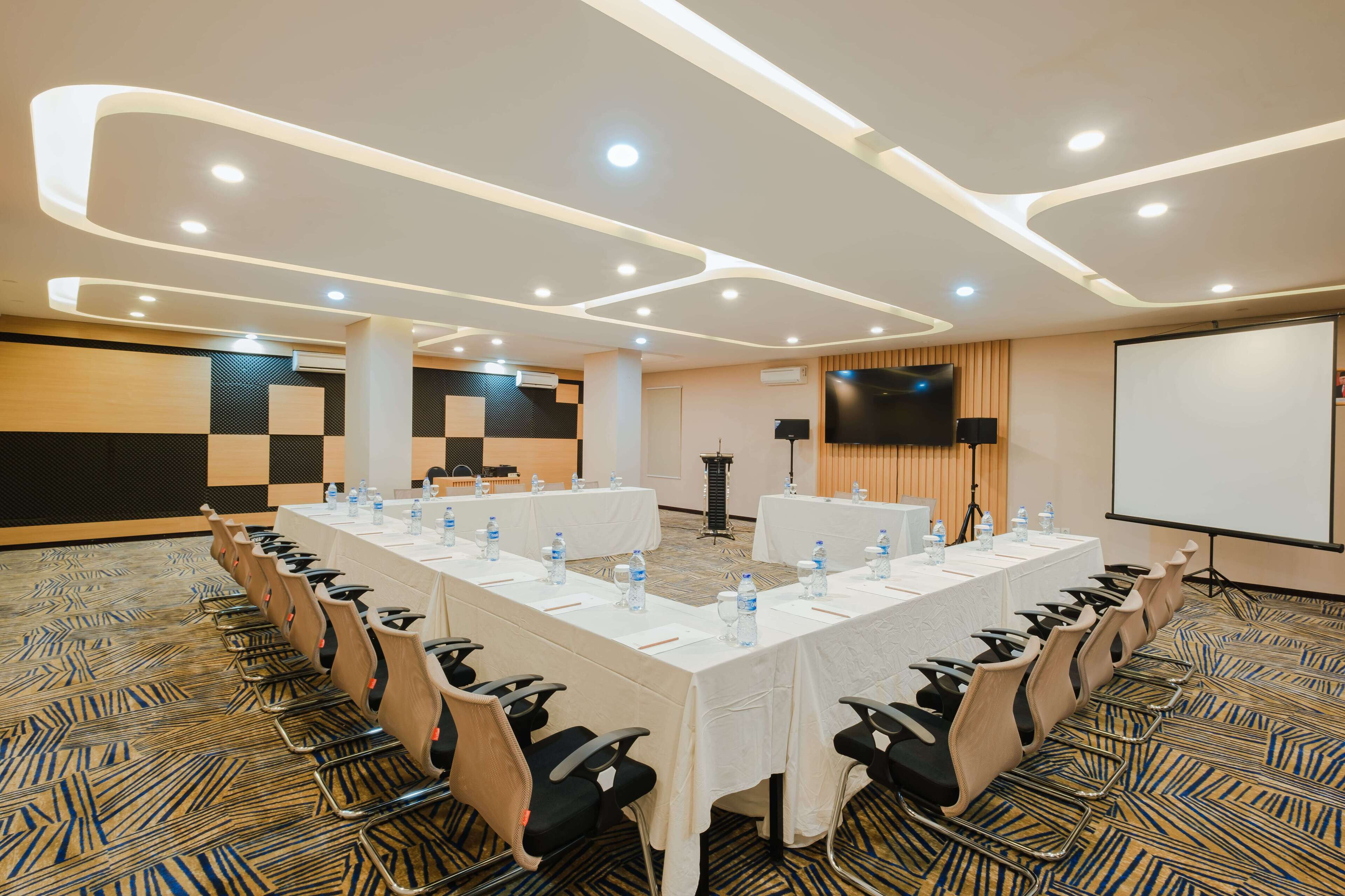 A conference room with a long table, chairs, a projector screen, and a whiteboard.