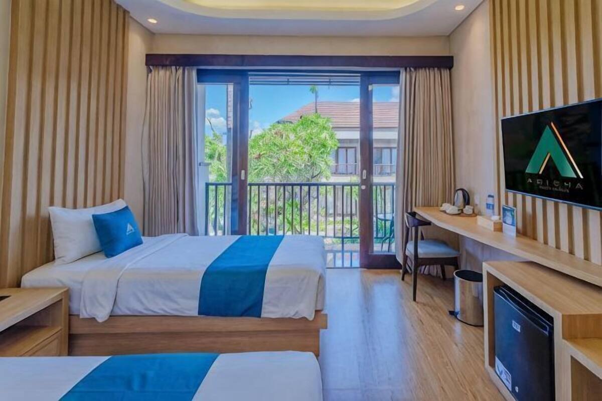 A hotel room with two beds, a desk, a TV, and a balcony with a view.