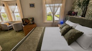 A hotel room with a bed, a dresser, a TV, and a view of a park and Ferris wheel. - Smartsway Hotel & Wellness (Eastbourne)