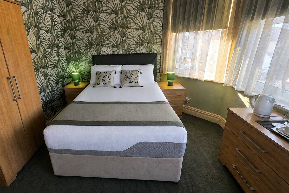 A bedroom with a bed, a wardrobe, a nightstand, and a dresser.